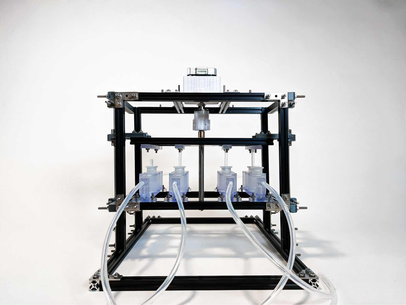Front view. Stepper and lead screw up top drive the actuation platform; the clear biocompatible-resin wells sit in the array below, plumbed with silicone tubing.